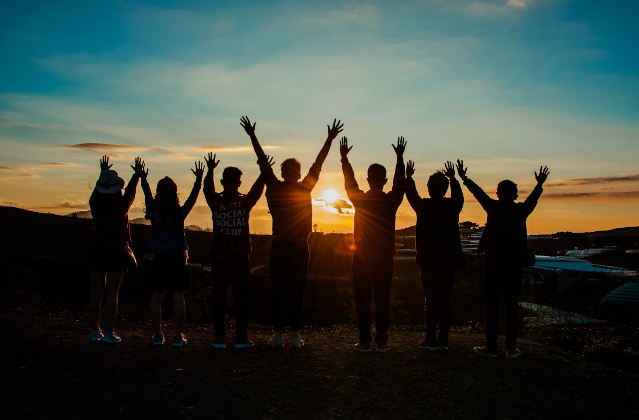pexels-photo-853168 A diverse group of friends raises their arms in celebration against a vibrant sunset backdrop.